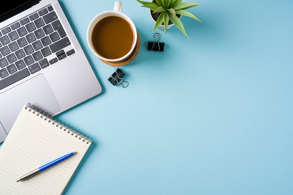 Professional office desk workspace with laptop, coffee and stationery items
